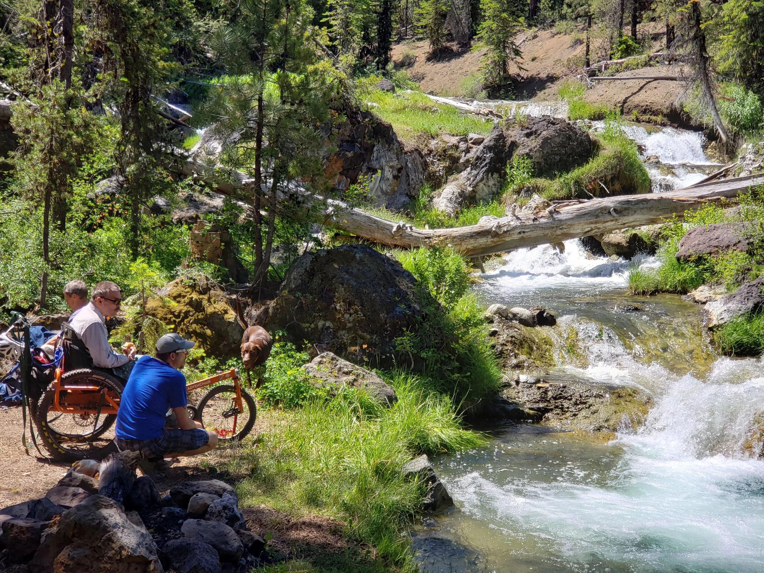 An AdvenChair user and his friends watch as crystal clear water cascades over small waterfalls at Paulina Creek