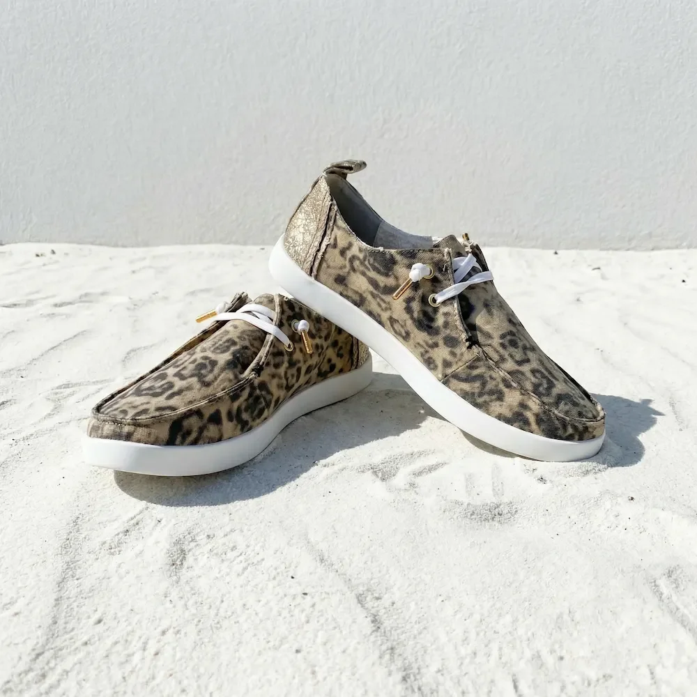 Pair of leopard print sneakers with white soles on a white surface.
