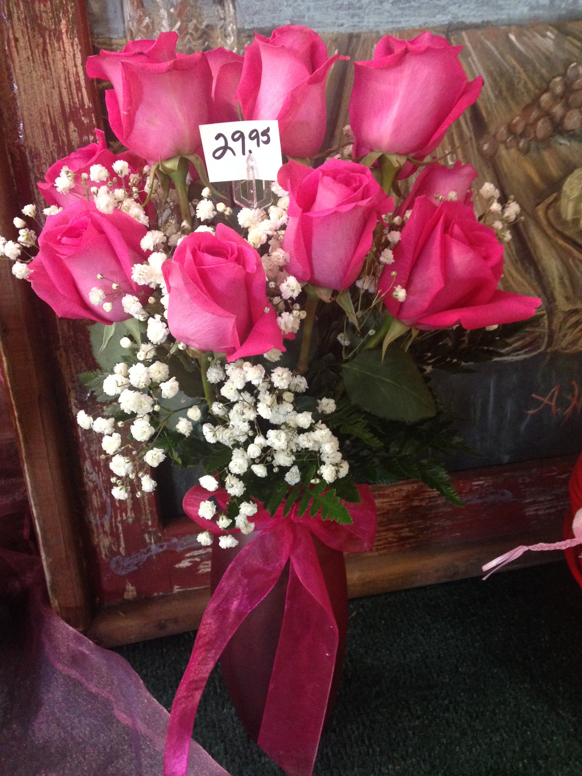 10 roses with greenery and ribbon in colored vase