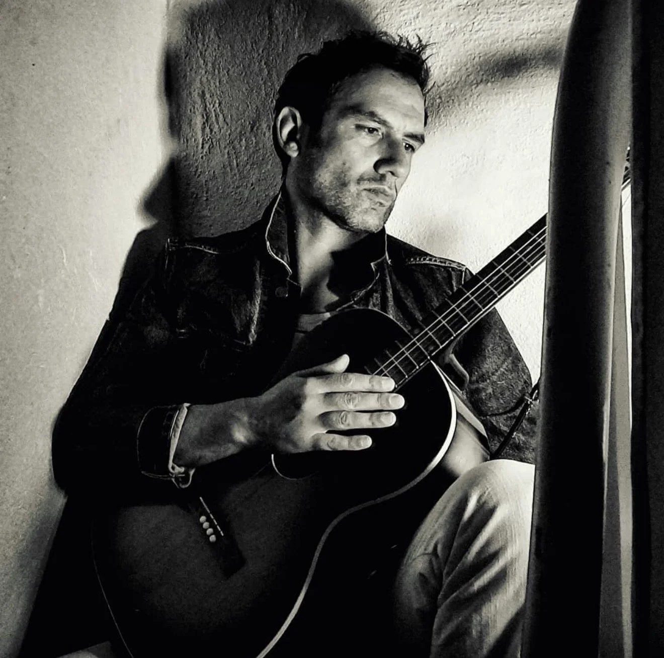 ack Rubinacci, singer-songwriter, black and white portrait with acoustic guitar