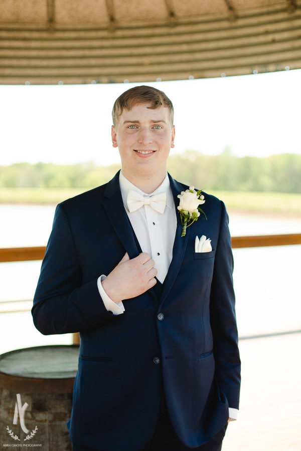 Groom in a navy suit with a white rose boutonnière 