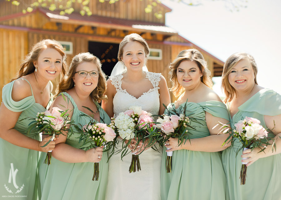 Bridesmaids wearing teal dresses and holding pink rose bouquets