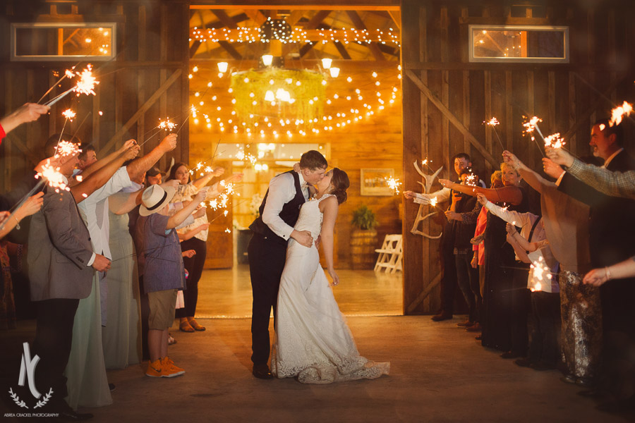 Bride and groom kiss for the sparkler exit at their rustic barn wedding