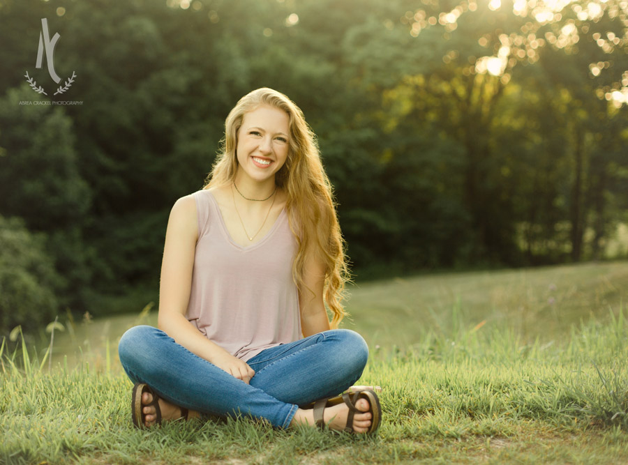 High School senior girl sitting in grass at sunset in Martin, Tennessee 