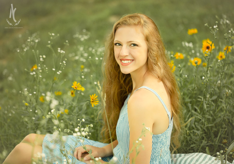 High School Senior sitting in patch of wildflowers in a blue dress