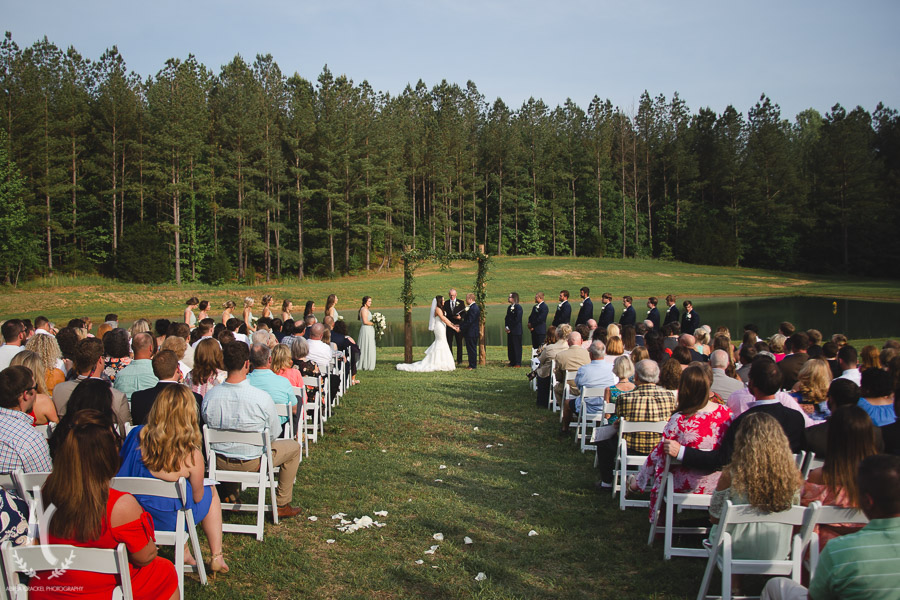 Outdoor Summer ceremony in front of pond and trees 