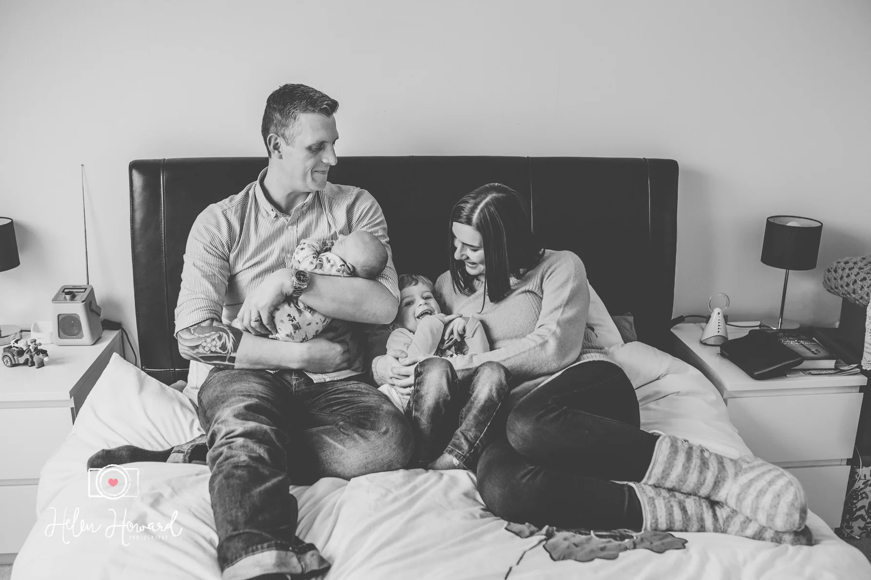 A family of four sitting on their bed for a portrait session