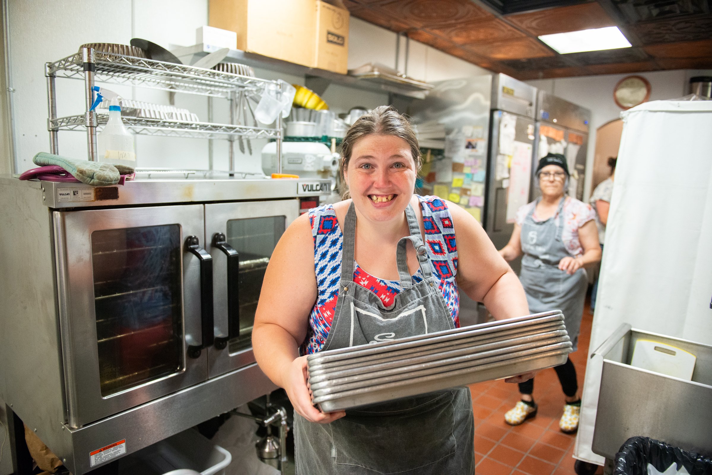 Helen puts clean dishes away at Soltane Café