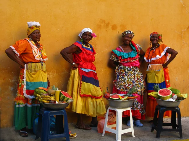 The iconic colorfully-clad, fruit-selling ladies you will see in Cartagena hail from Palenque. Source