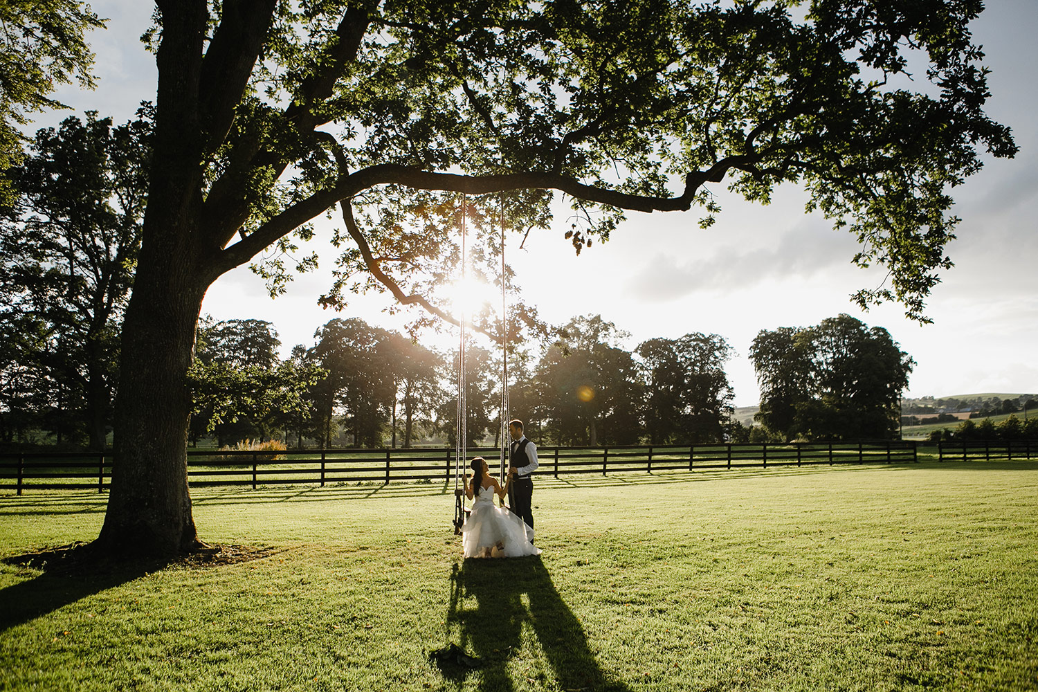bride and groom on swing sunset photo