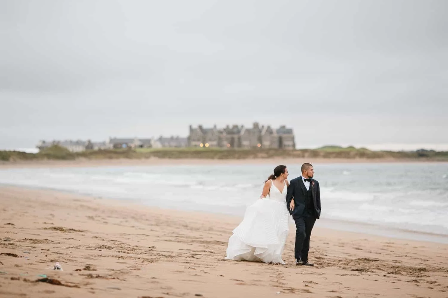 Bride and Groom Walking on the Beach Outside Trump Doonbeg Hotel