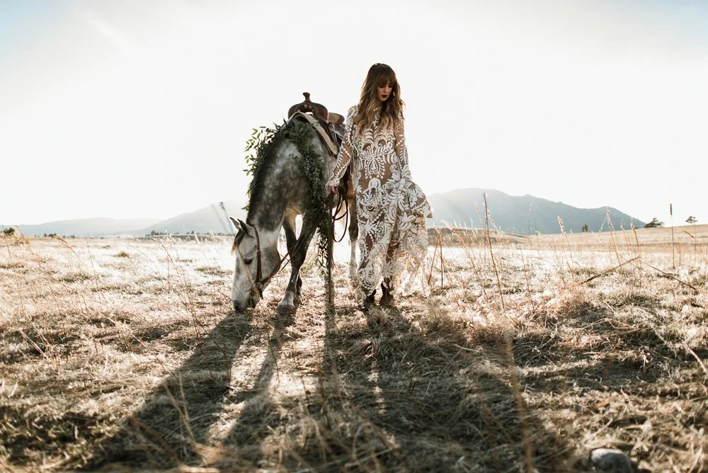 Woman in lace dress walking with horse in field