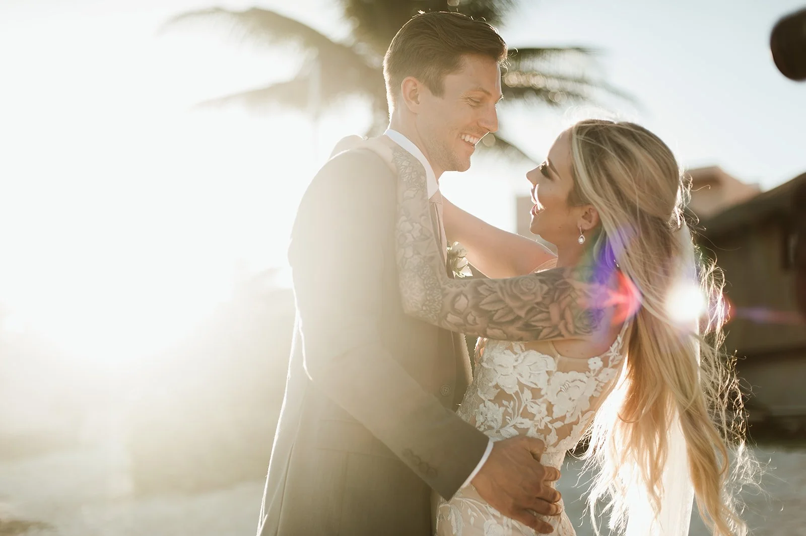 Bride and groom smiling at sunset during outdoor wedding.