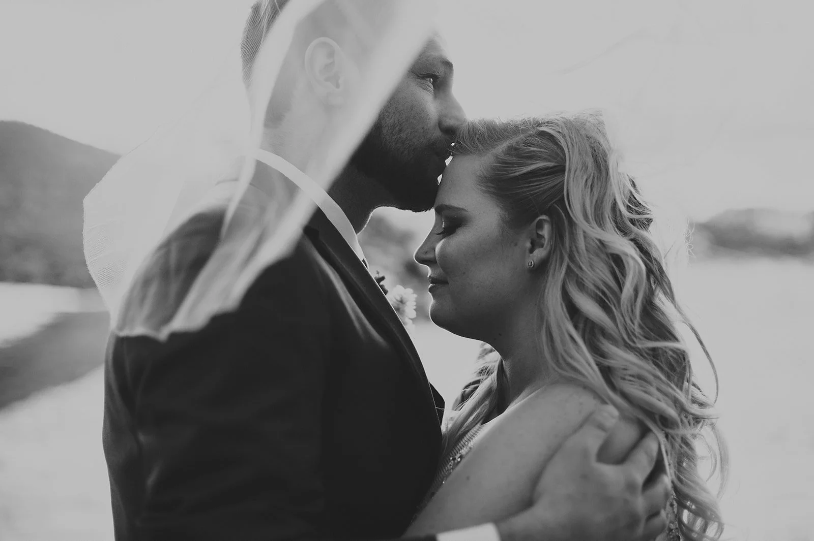 Romantic black and white photo of a couple embracing with a veil.