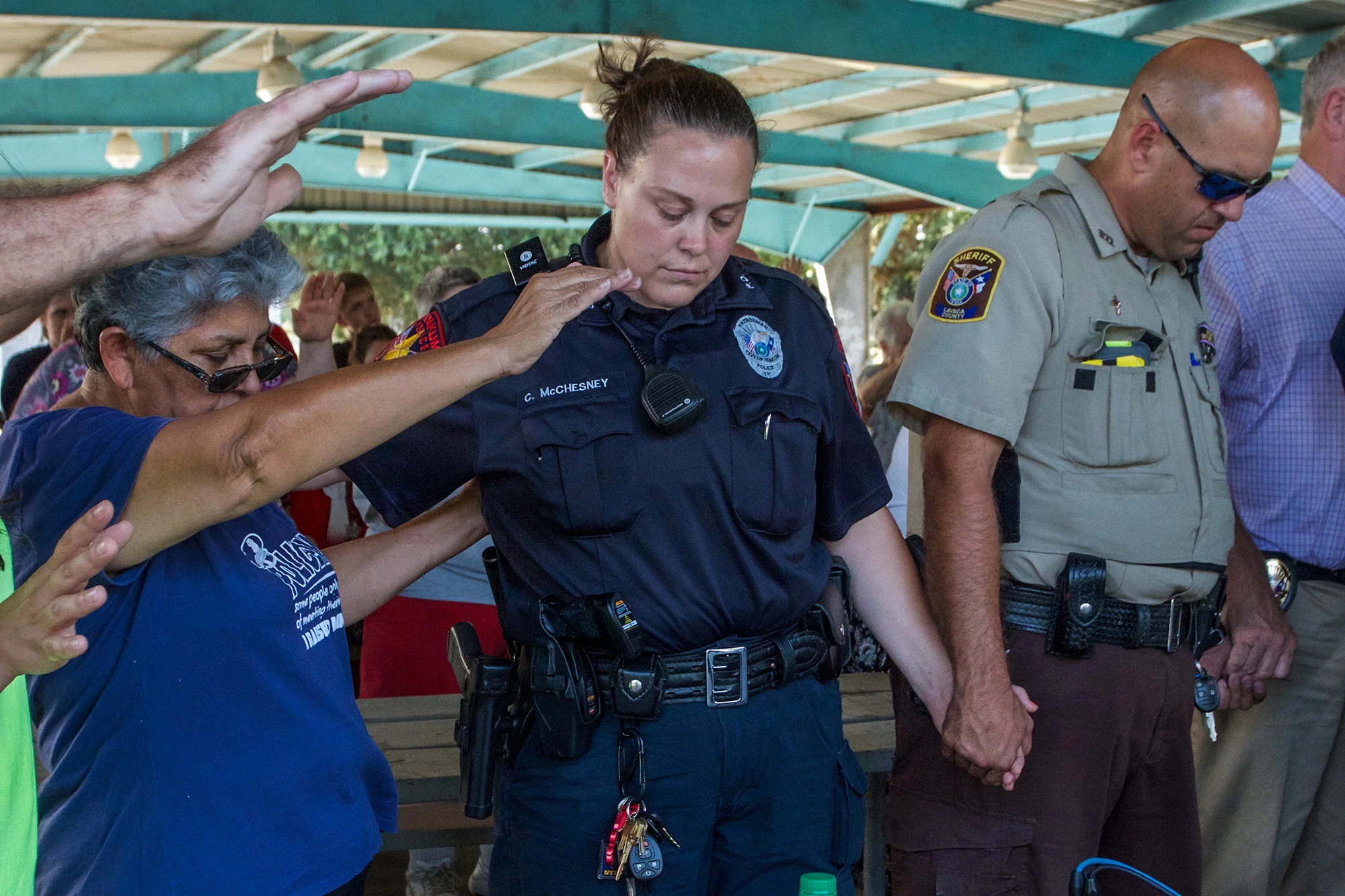Community member Frances Barrera (left), places her hand over Yoakum Police Officer Christi McChesney and Lavaca County Patrol Deputy Jimmie Heiman during a prayer asking for protection and safety for those working in law enforcement.