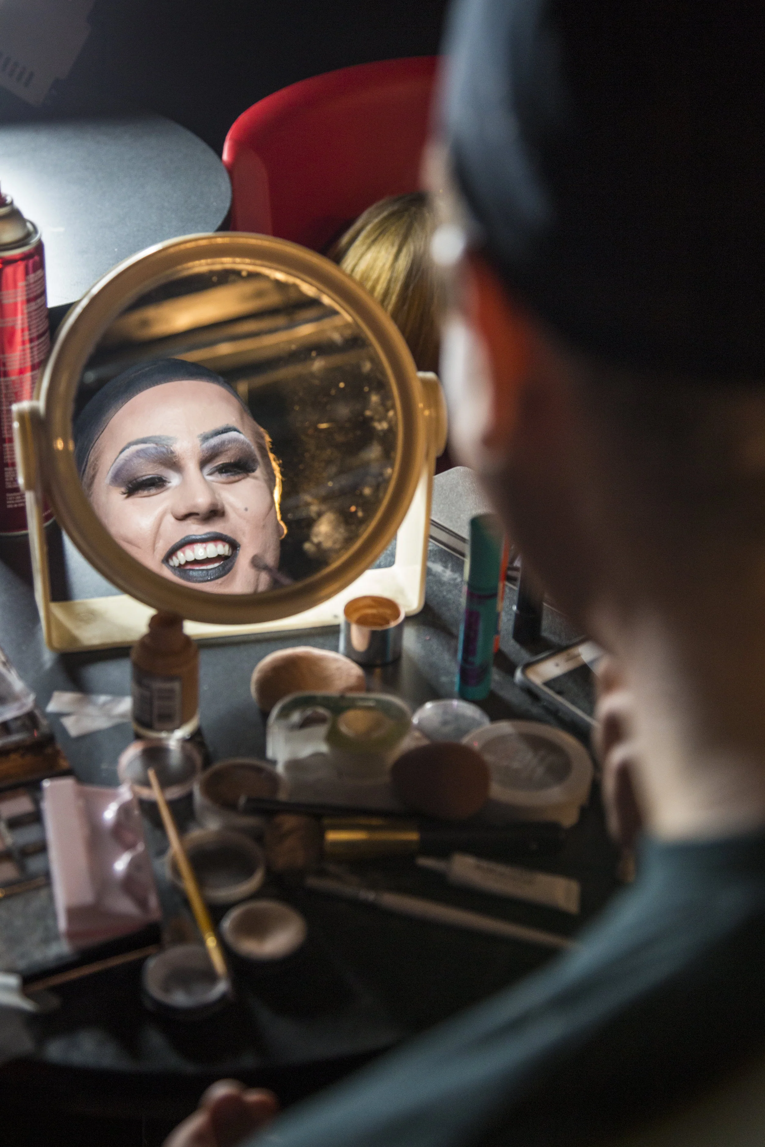 Drag newcomer Austin Drew smiles as he puts on makeup and jokes with other queens in the room while they all get ready for the Burnin’ Up Drag event.