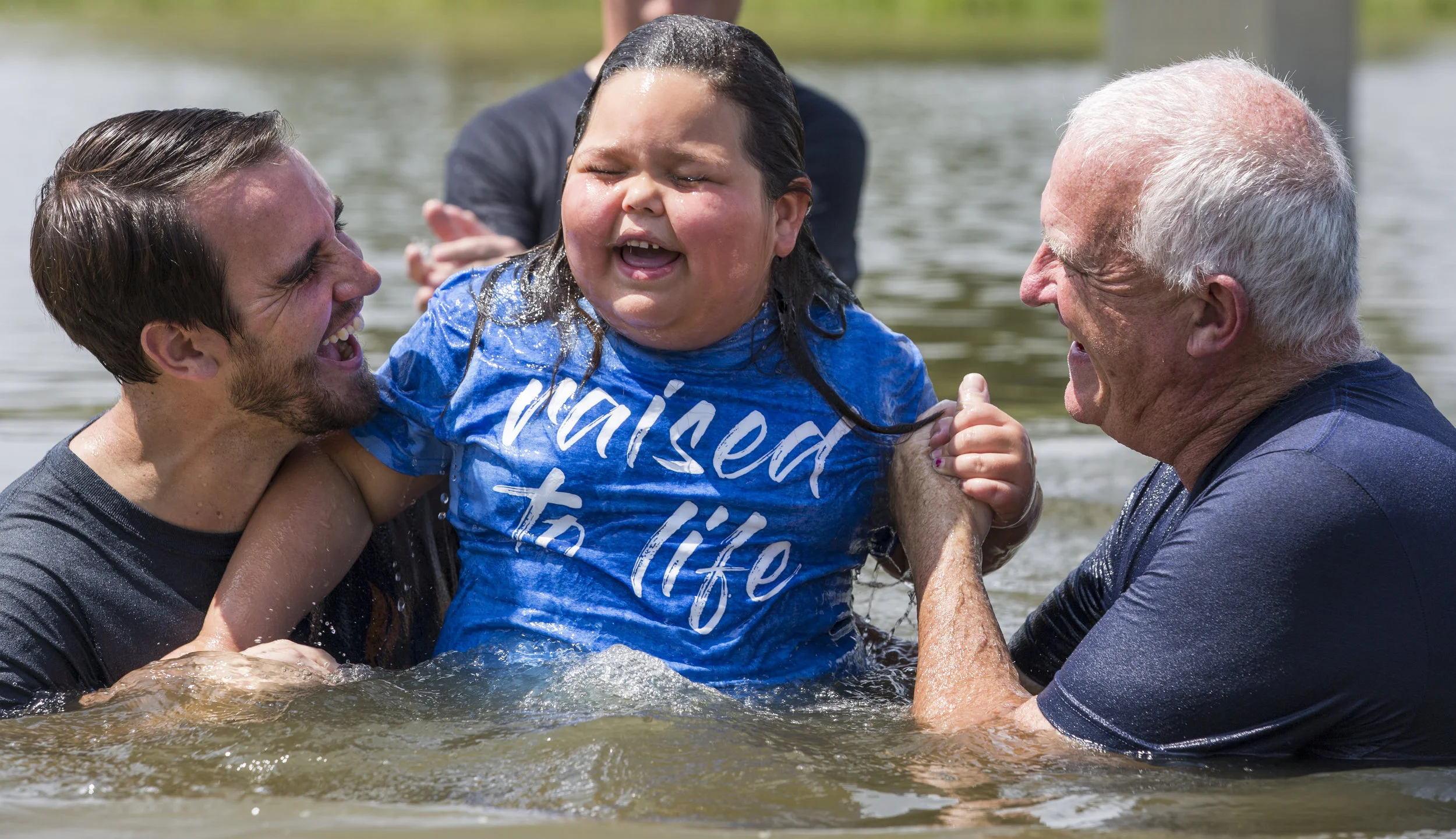 Pastors of Brandywine Church in Greenfield, Indiana smile as one of their young members gets baptized. Nearly 100 people were baptized in the pond just outside of the church on that Sunday. @Savannah Blake