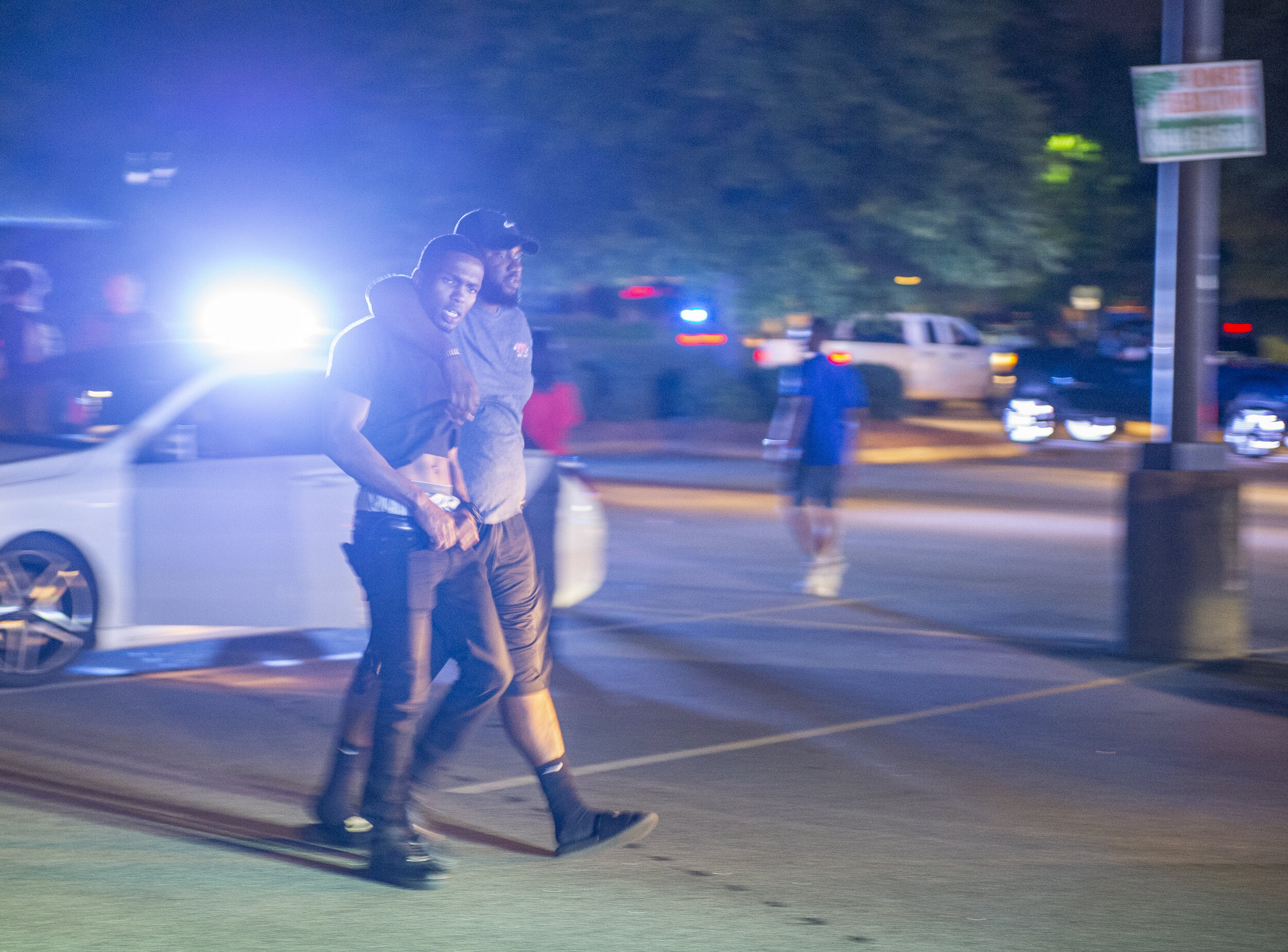 As protesters are forced to leave by Greenville police two men hold onto each other as they walk towards officers to get in their car.