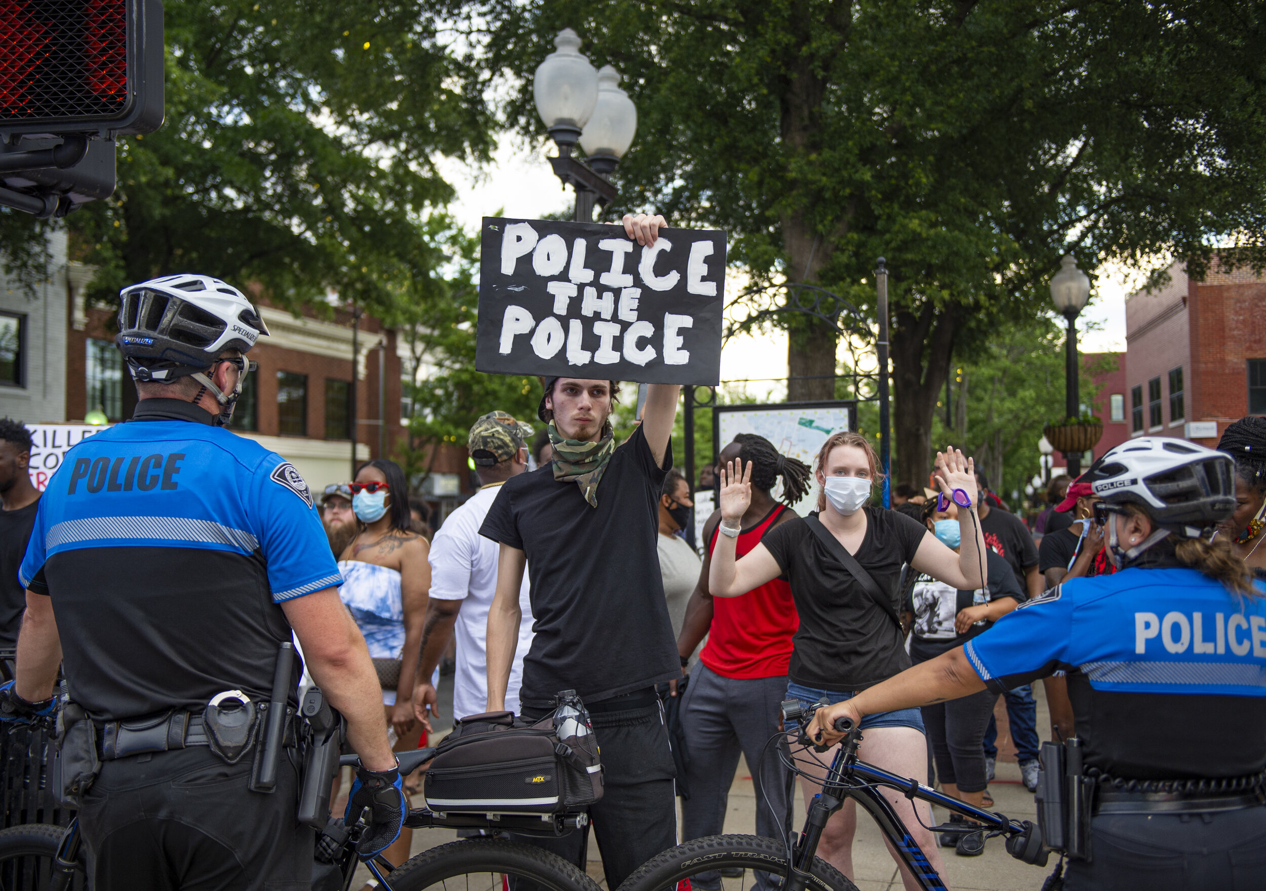A protester silently holds up a sign towards a line of police officers in downtown Greenville.