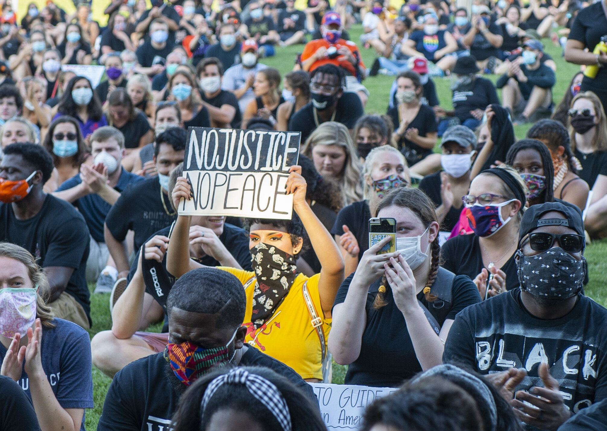 The sunlight hits a protester in the crowd as she holds up a “No Justice - No Peace” sign during the peaceful protest event.