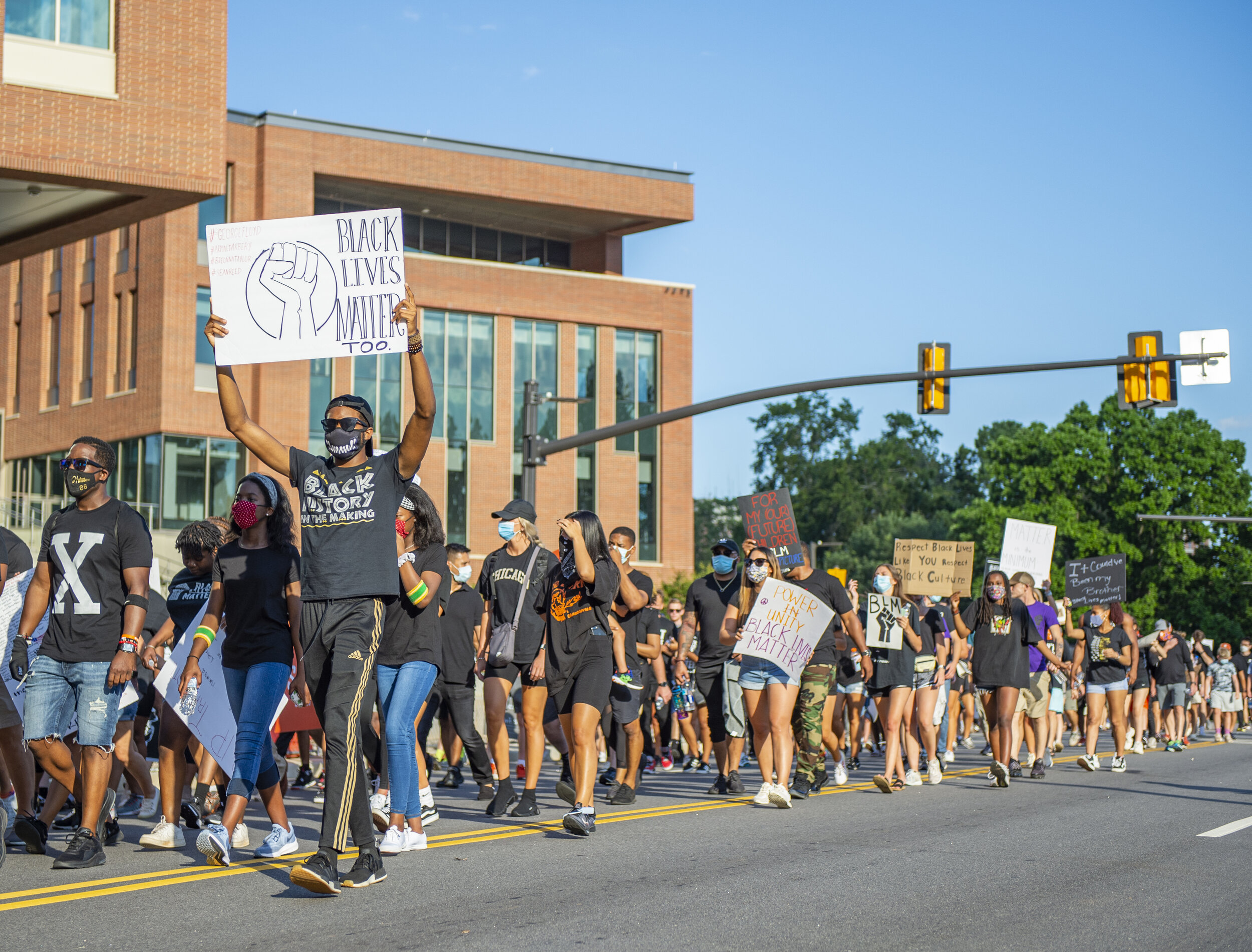 A peaceful protester holds up a Black Lives Matter Too sign while marching around the Clemson University campus.
