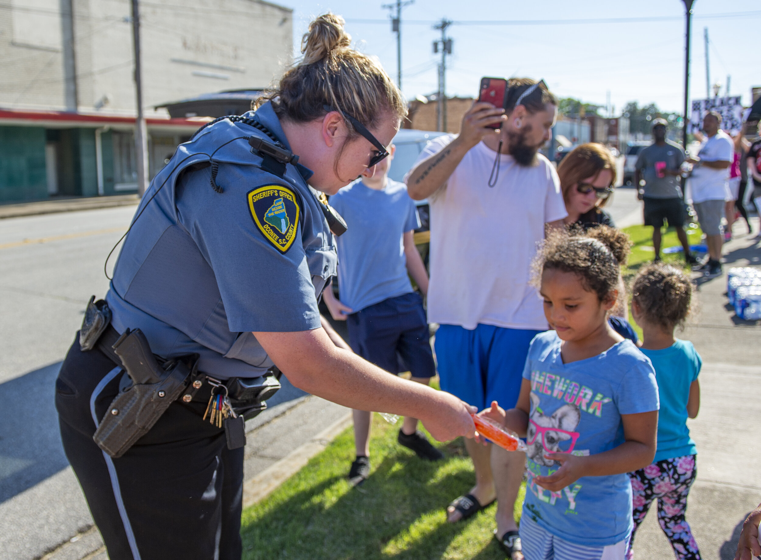 Officer Calley Moore hands 6-year-old Myla Montgomery a popsicle during the George Floyd protest outside of Seneca City Hall.