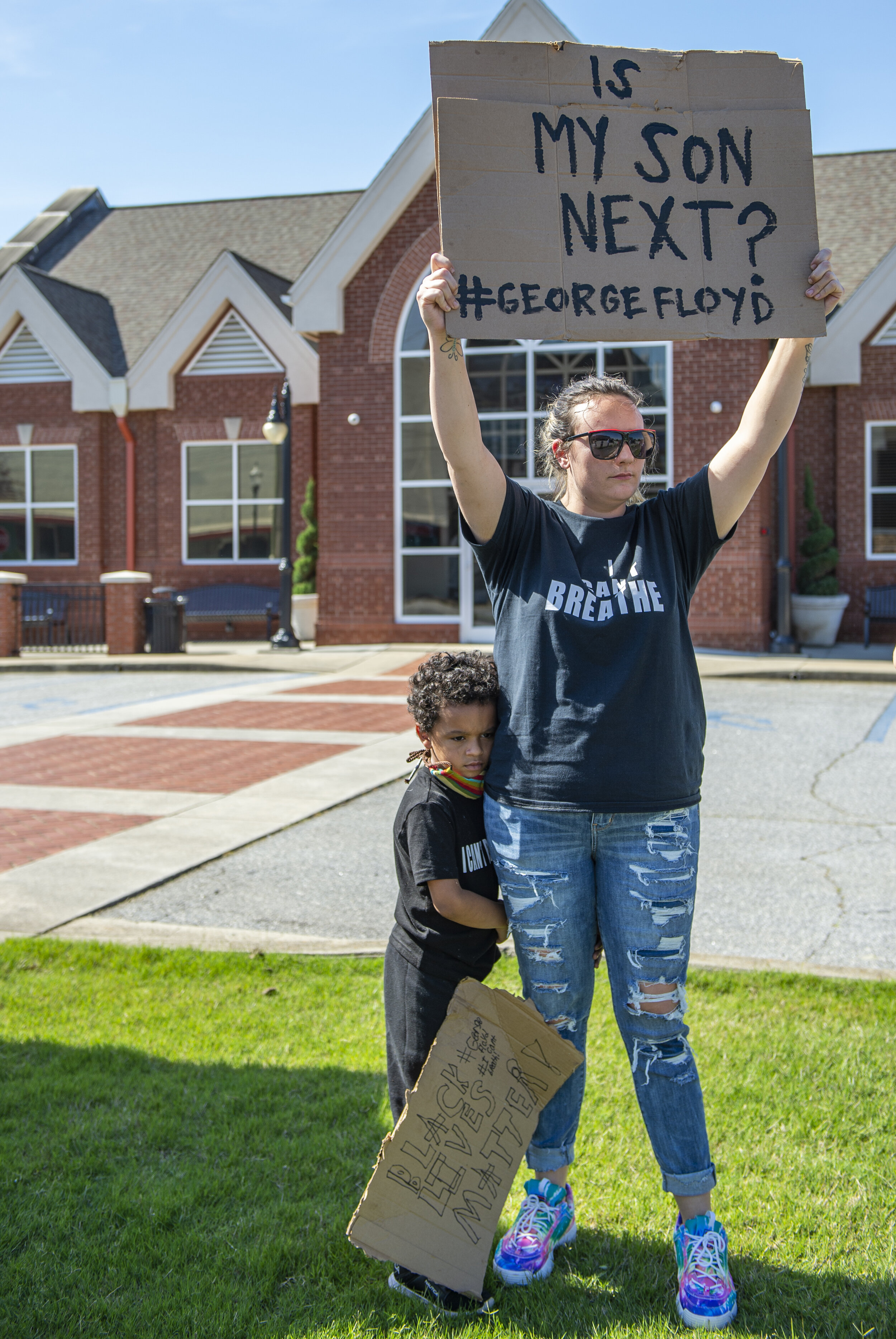 Betty Jo Smith holds up a sign as her five-year-old son Kyrie Jenkins hugs her side during the George Floyd protest.