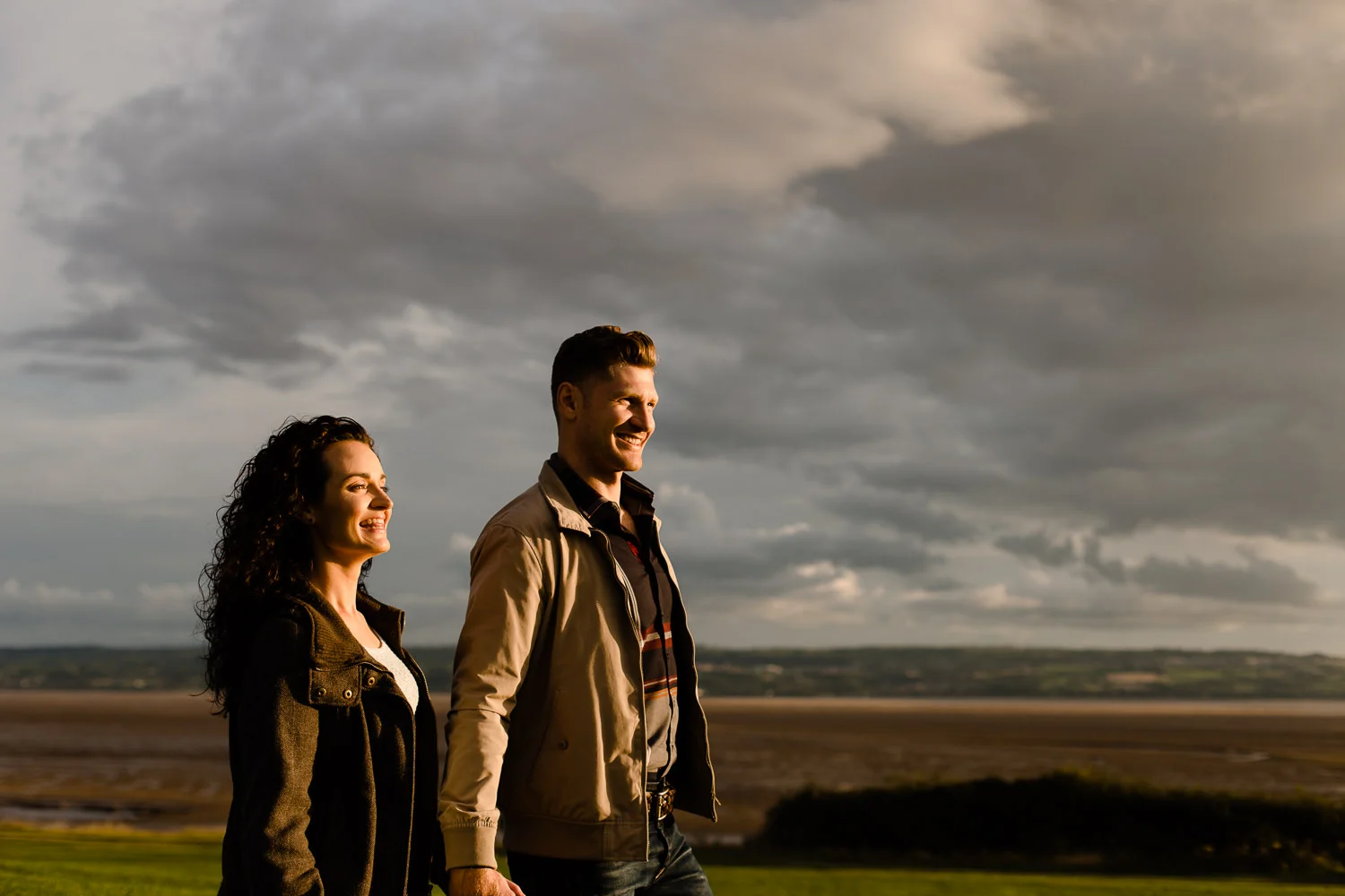 Couple walking towards the sunset over looking the bay in Wirral
