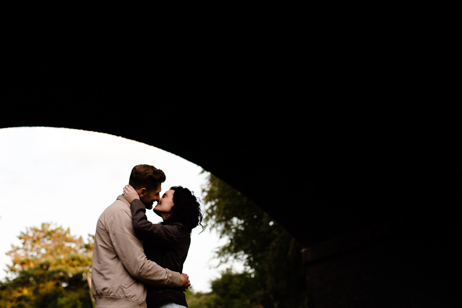 A couple kiss under a bridge