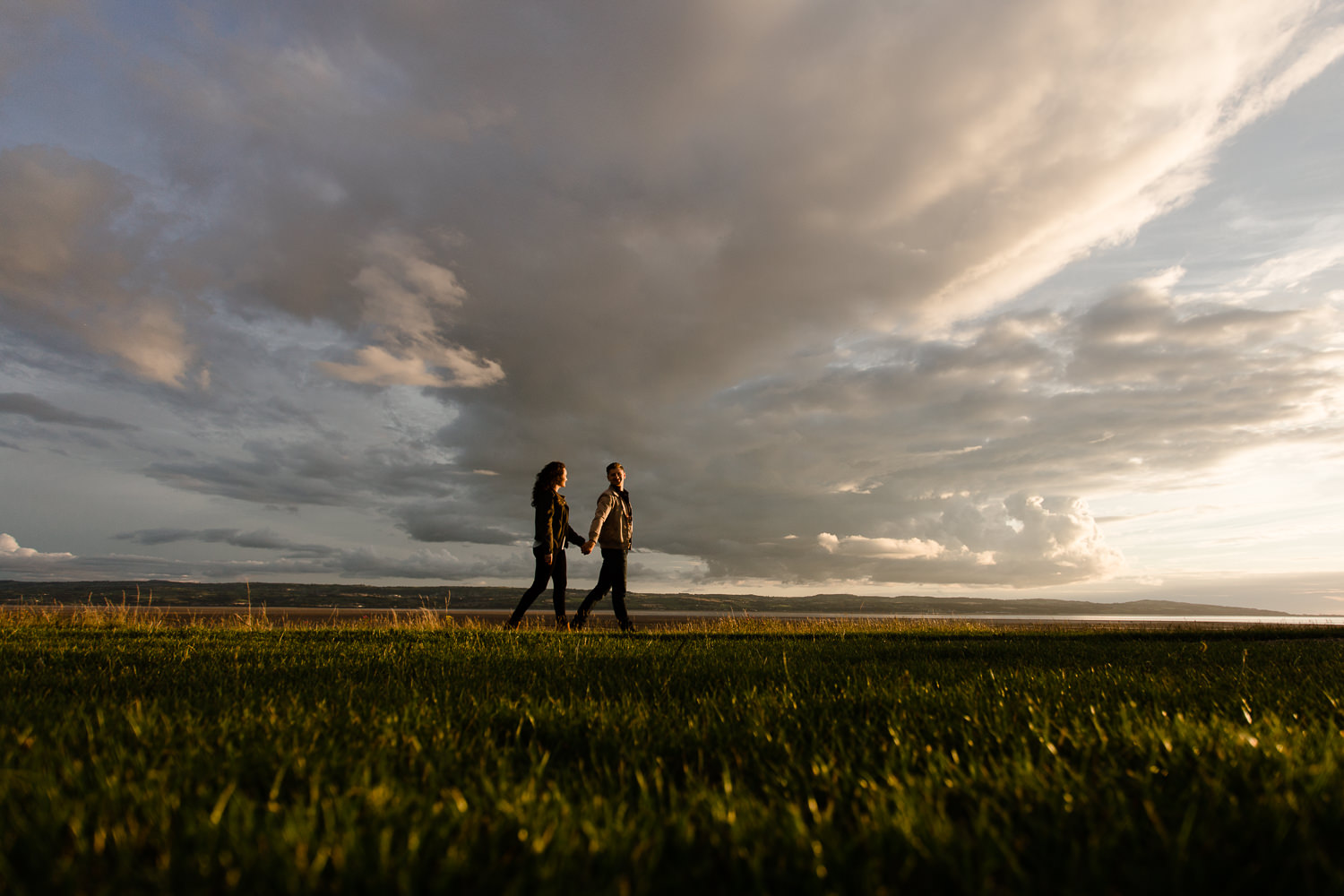 A couple walking past epic Wirral skies - Merseyside pre wedding shoot
