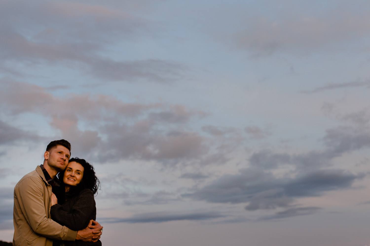 A couple watching the sunset placed against the sky