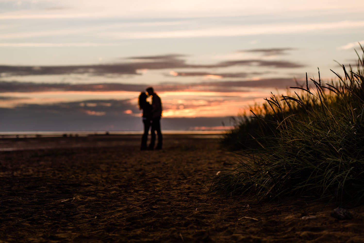 A couple silhouetted against the sunset key on the beach couple shoot