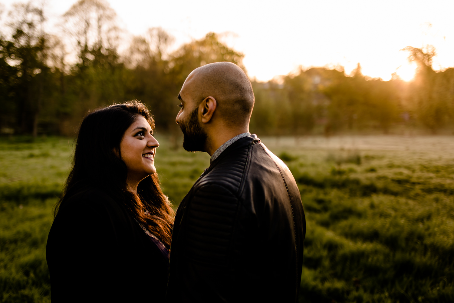 Couple looking at each other in the golden light of a sunrise over parkland