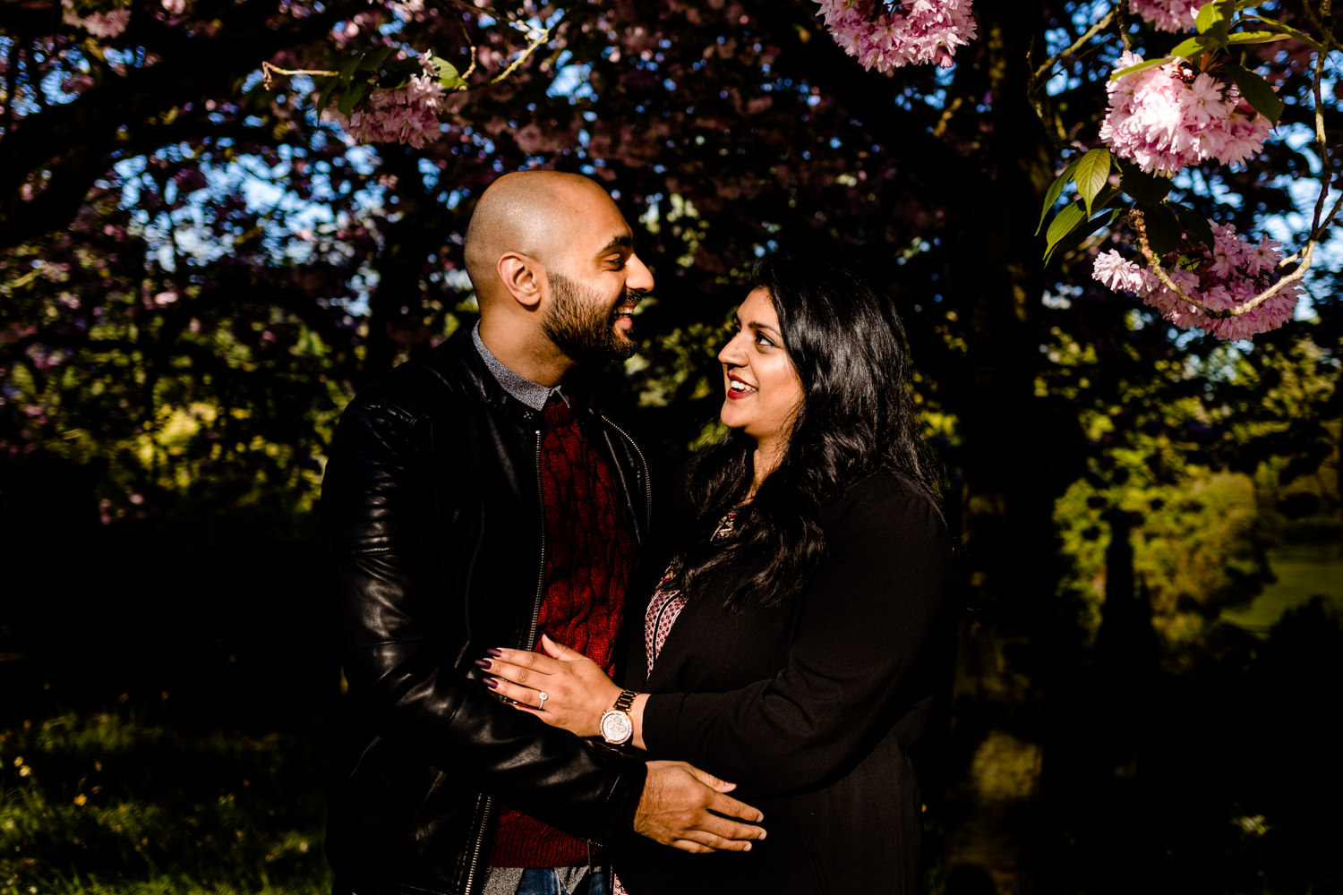 Laughing couple with a blossom tree on a pre wedding shoot.