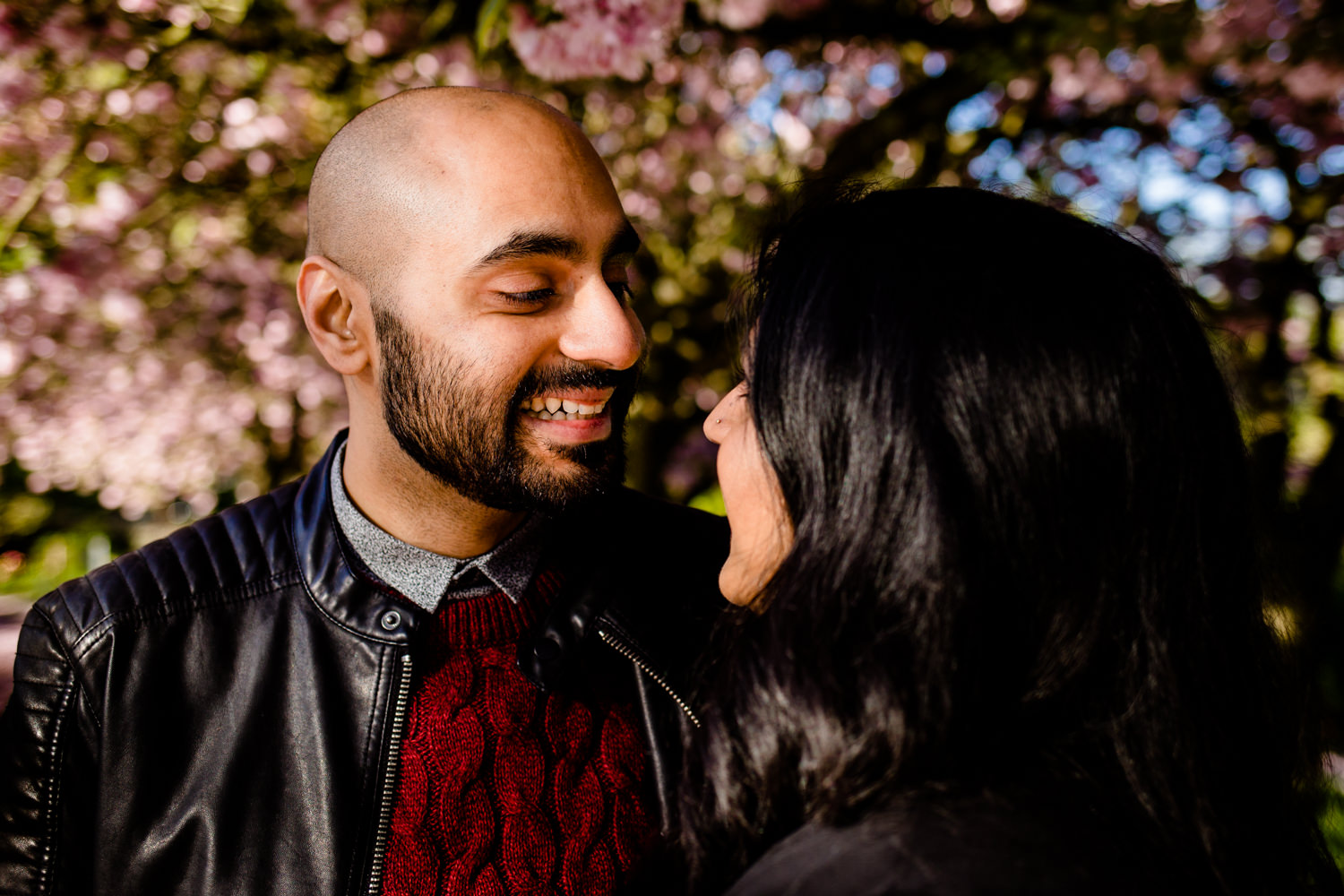 A man and woman looking at each other under a blossom tree in Manchester