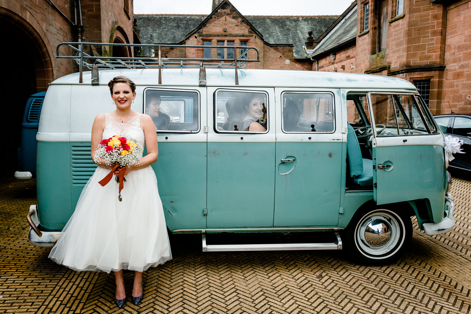 Kate, the bride, in a tea length wedding dress stood by a vintage green VW camper van in Cheshire wedding venue in Wirral, Thornton Manor. 