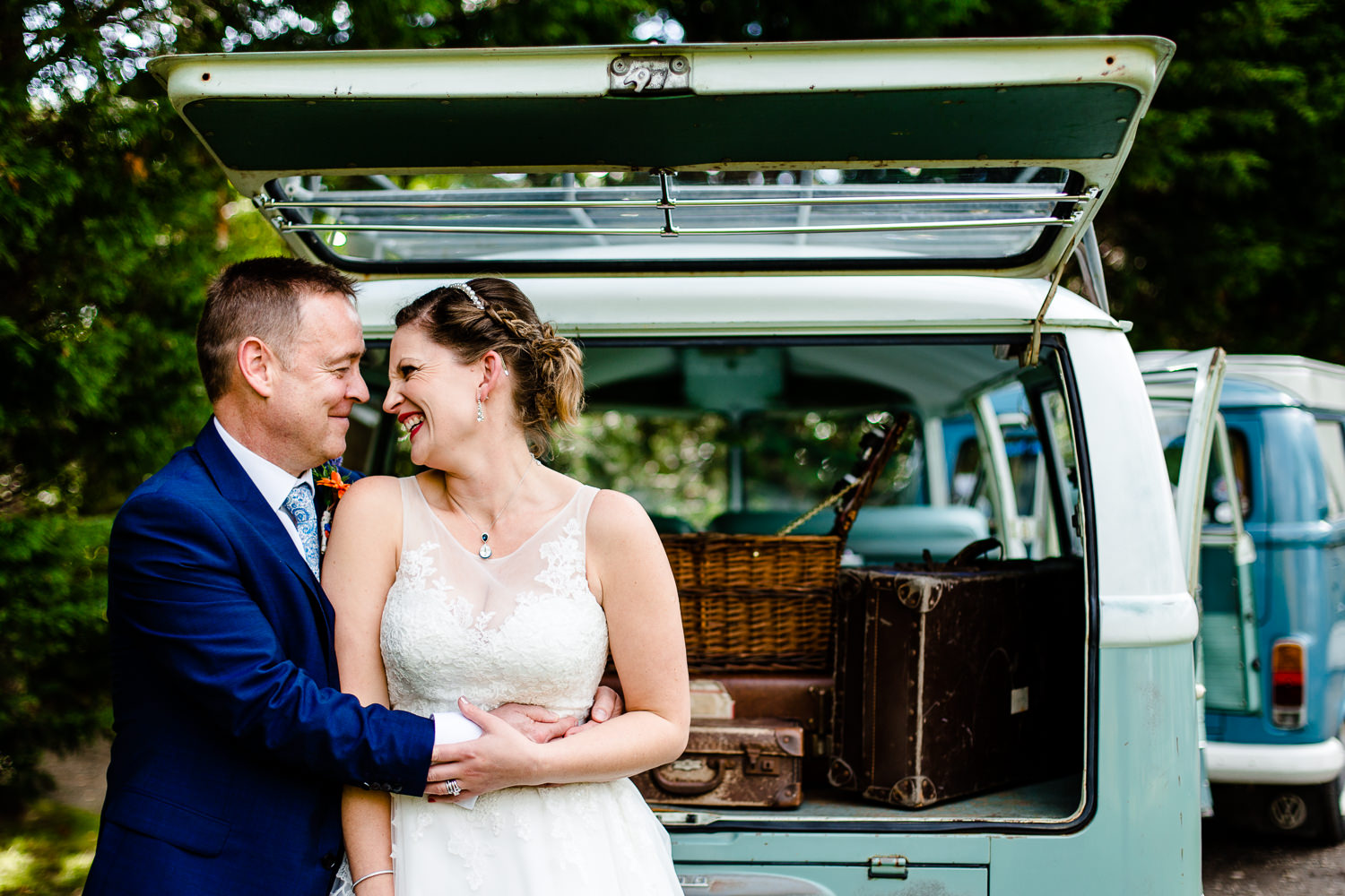 A bride and groom cuddle in front of a green vintage VW camper van by Thornton Manor wedding photographers in wirral