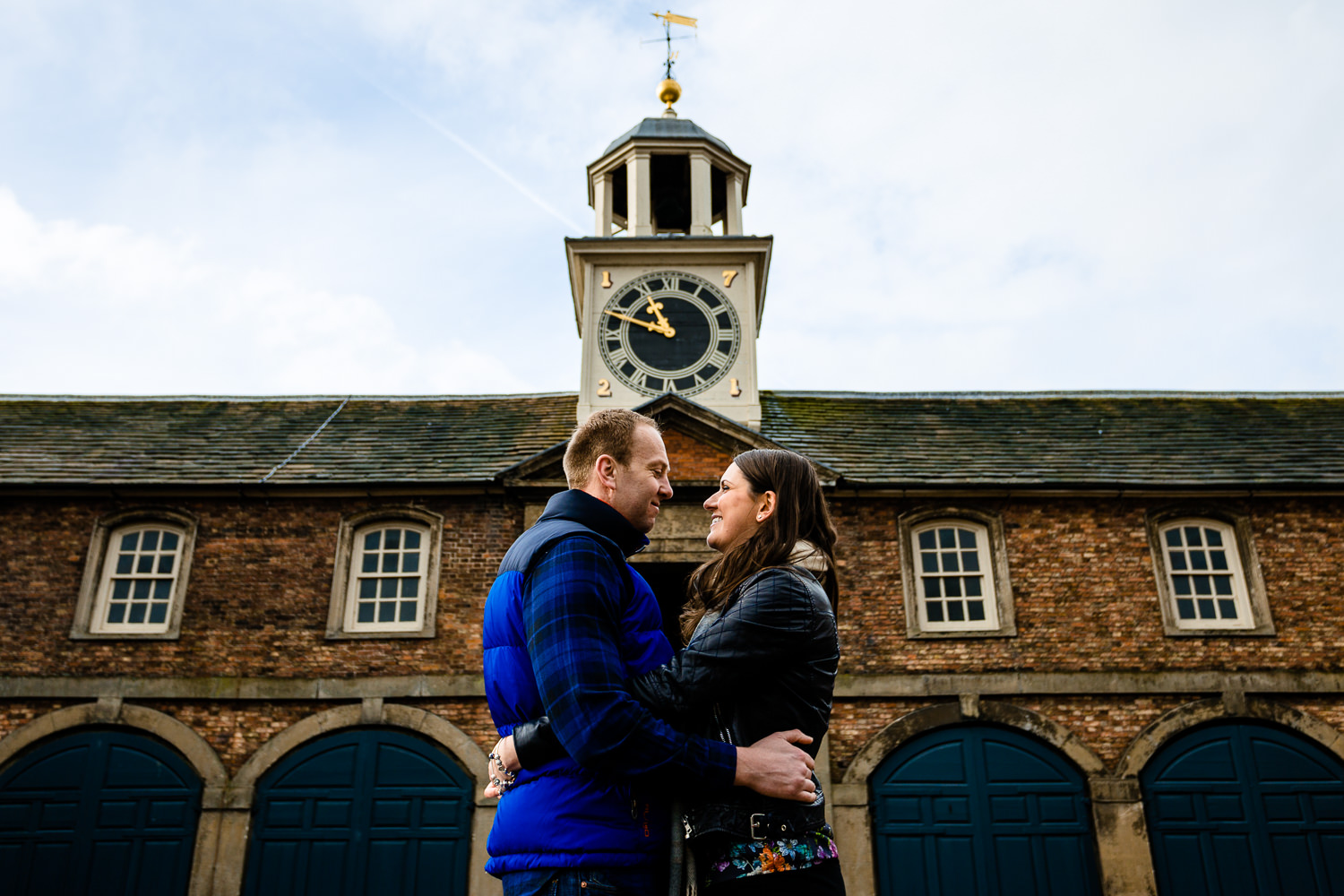 Claire & Damien cuddle in front of the clock tower at Dunham Massey on their pre wedding shoot.
