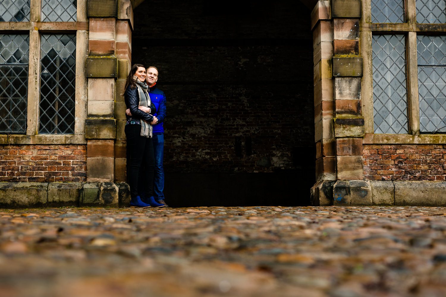 A Dunham Massey pre wedding shoot image of a couple stood in an archway.