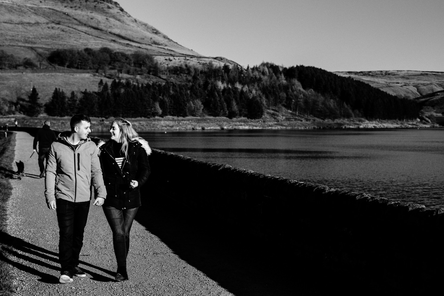 Engaged couple Sarah and Jason walking along side Dovestone reservoir. 