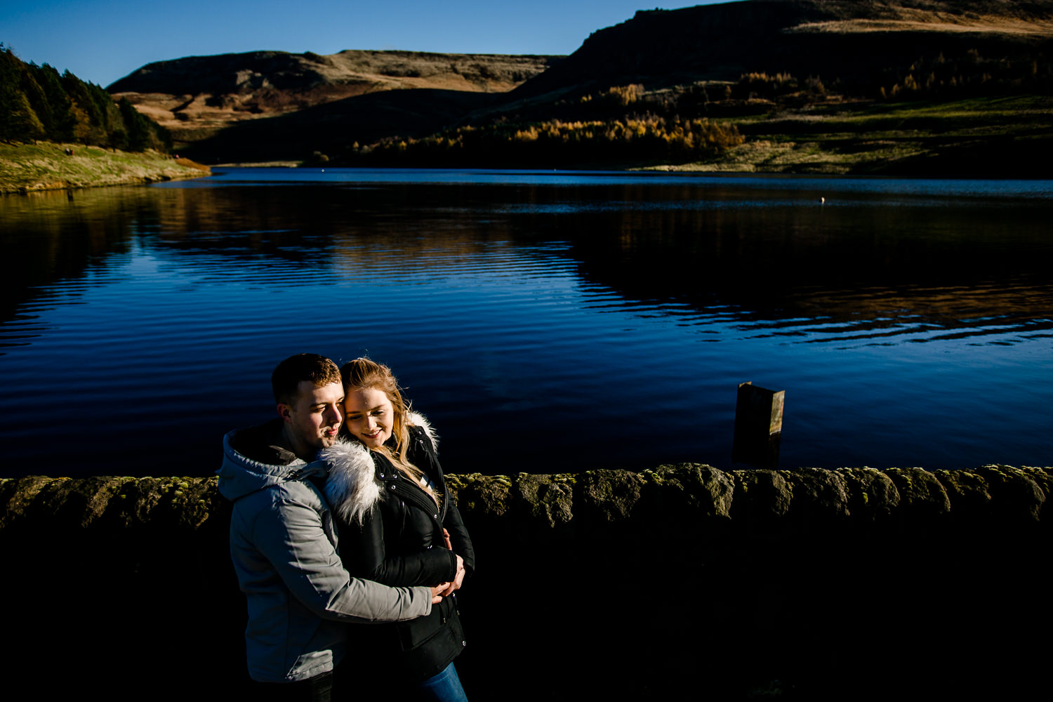 Cute couple, Sarah and Jason laughing and cuddling on their pre wedding shoot at Dovestone reservoir, by Manchester wedding photographers, Zoe & Tom. 