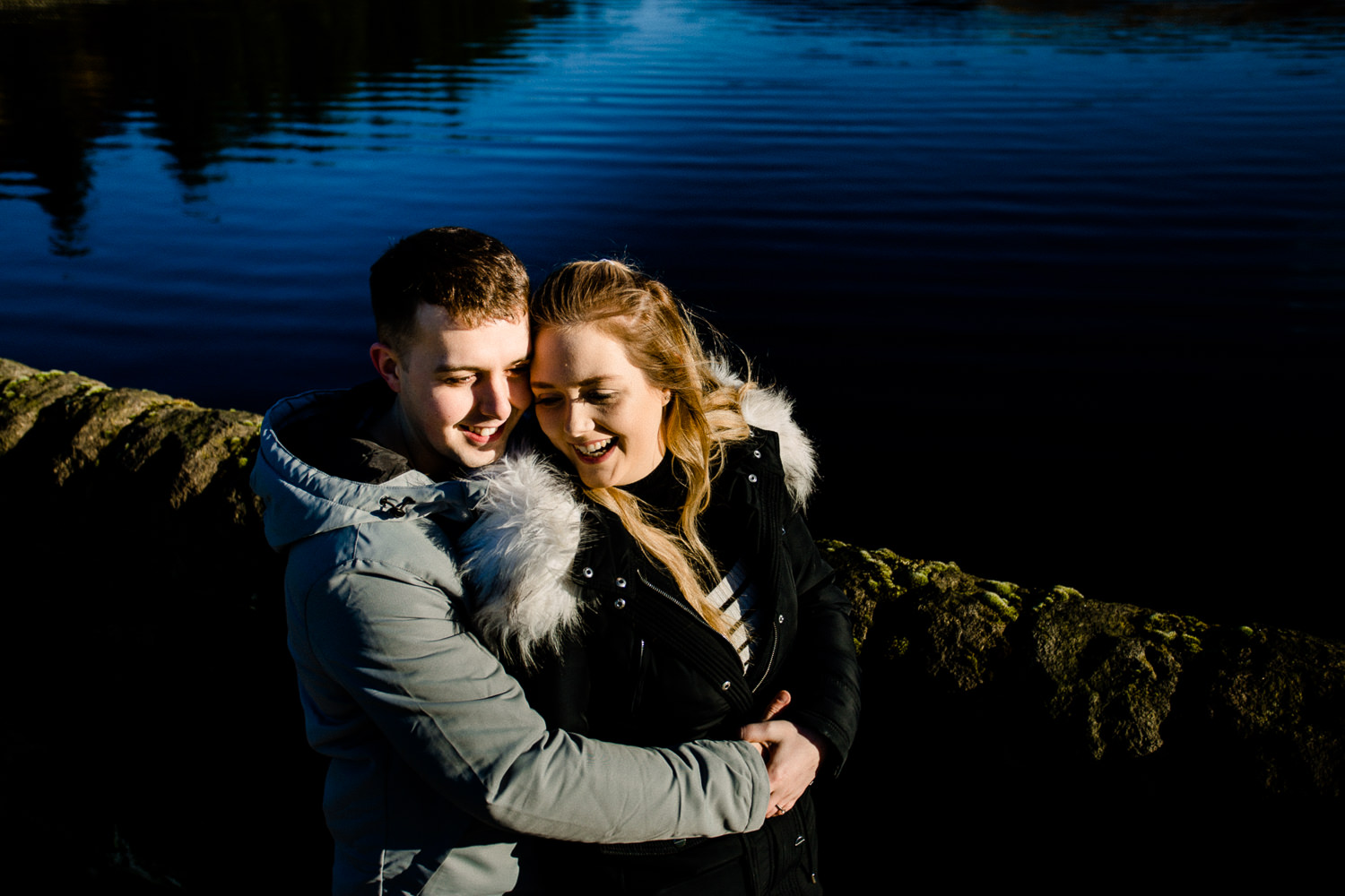 Cute couple, Sarah and Jason laughing and cuddling on their pre wedding shoot at Dovestone reservoir. 