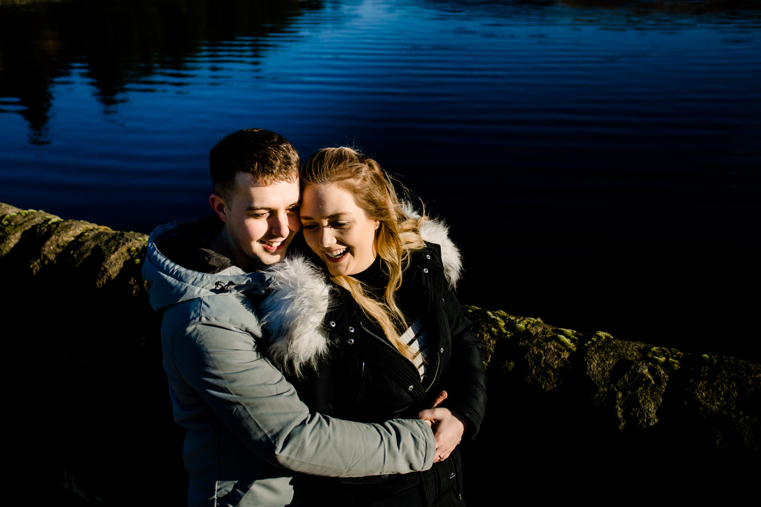 Cute couple, Sarah and Jason laughing and cuddling on their pre wedding shoot at Dovestone reservoir.