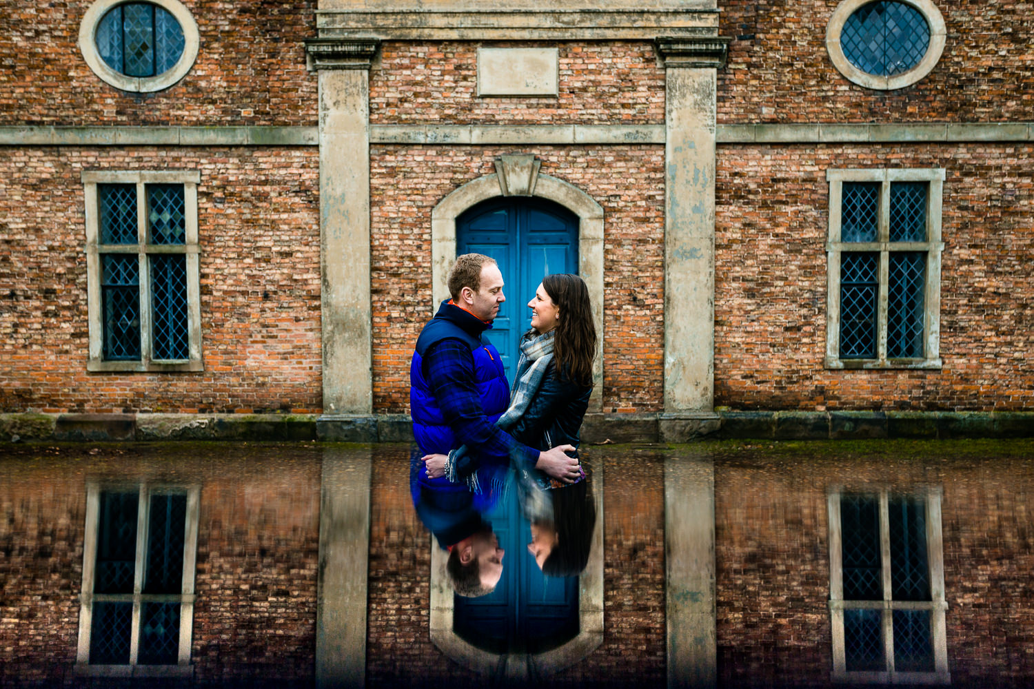 Dunham Massey pre wedding shoot, reflection image of a couple stood in front of an old building. 