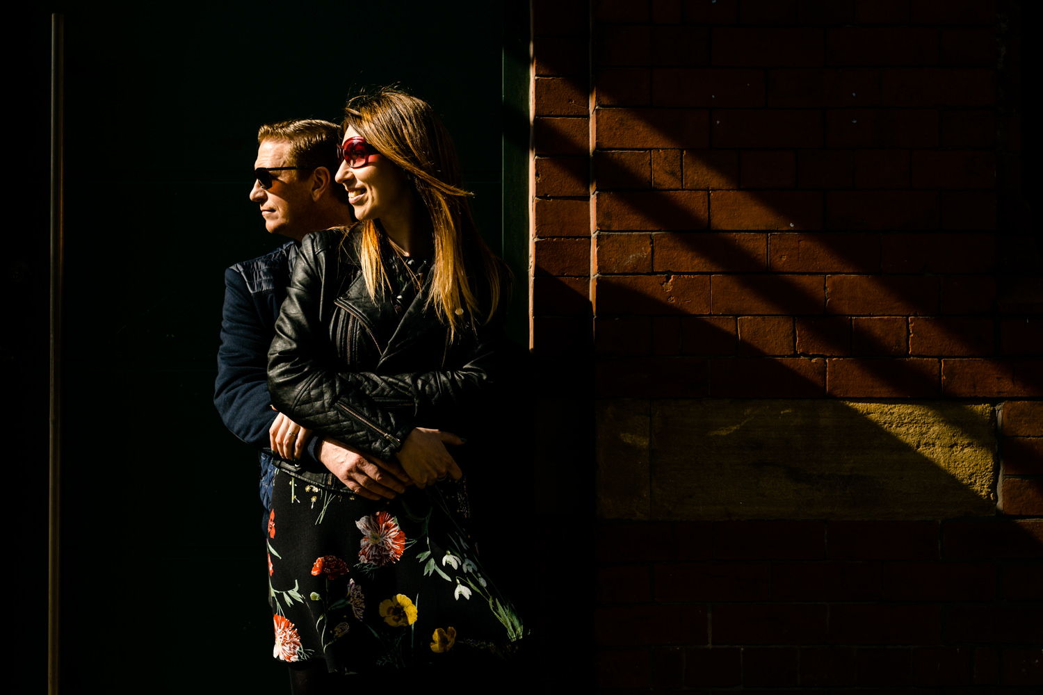 Sun shines on a cool couple in sunglasses on their Northern Quarter pre wedding shoot by Manchester wedding photographer. 