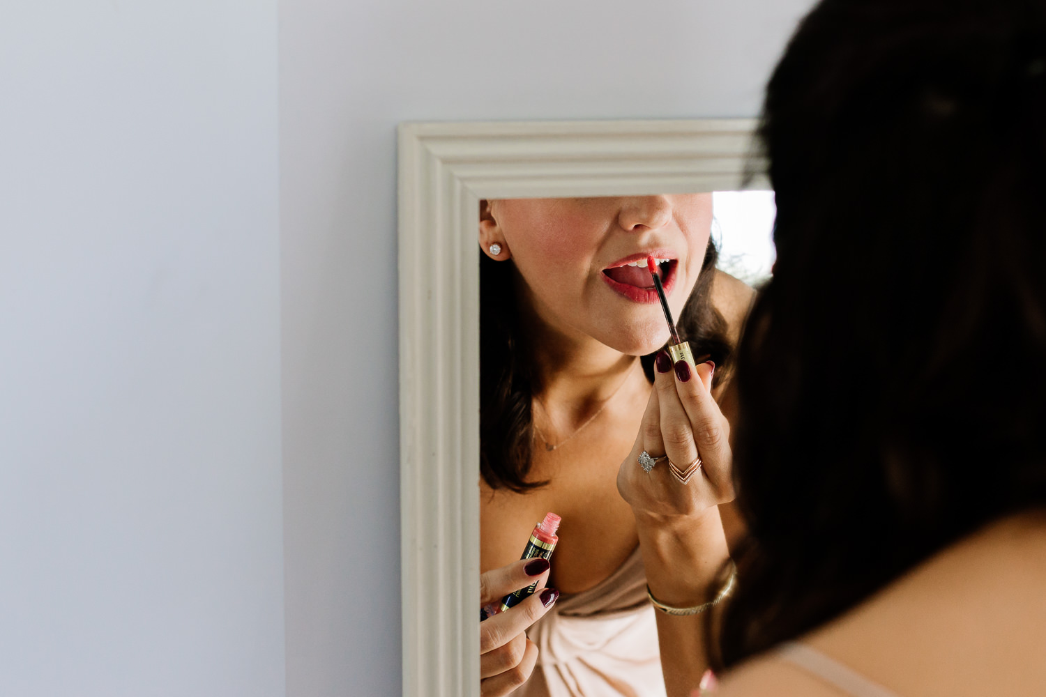 Bridesmaid doing her make up in a mirror, wedding photography. 