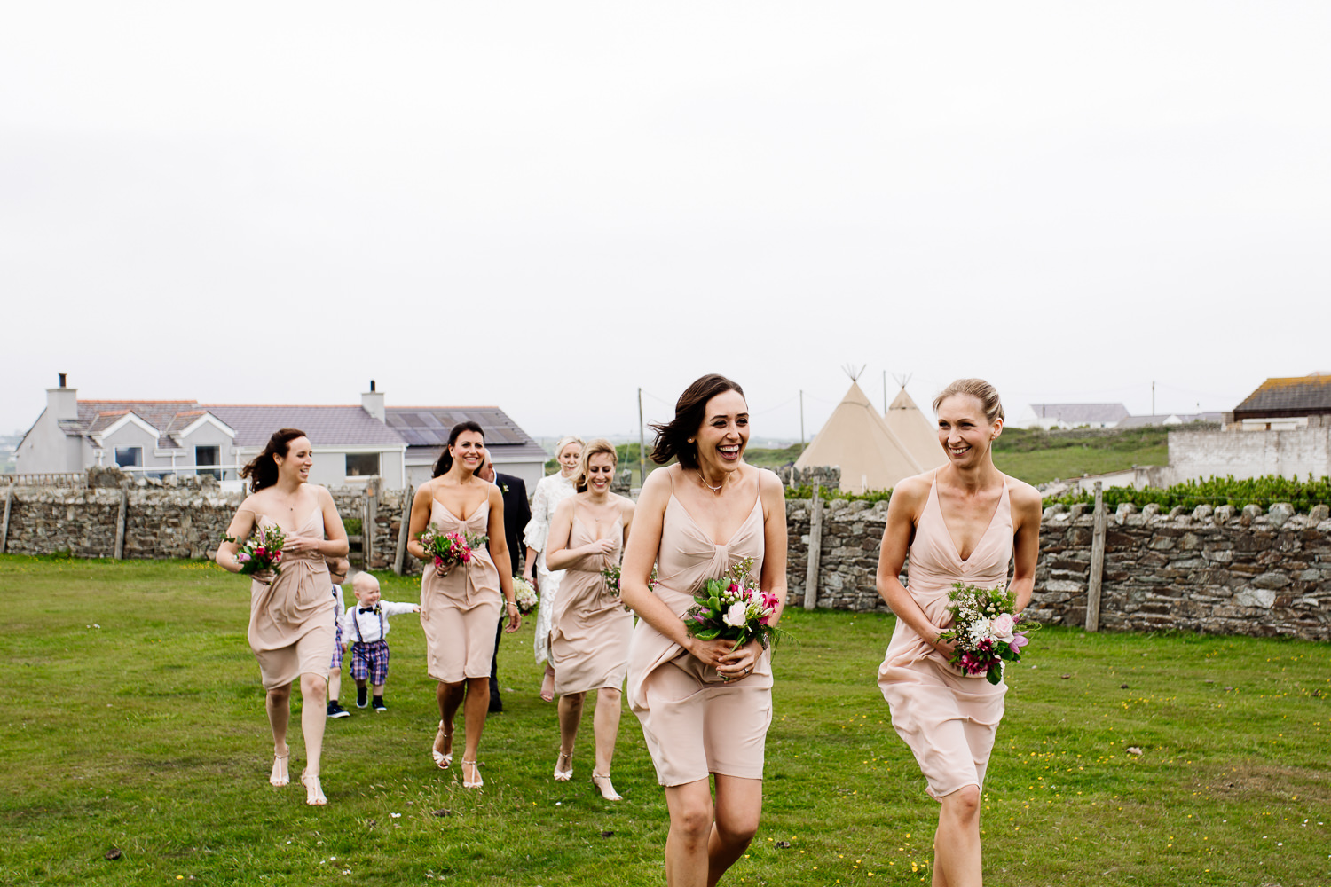 Bridemaids brave the windy headland in Anglesey, wedding photographer Wales. 
