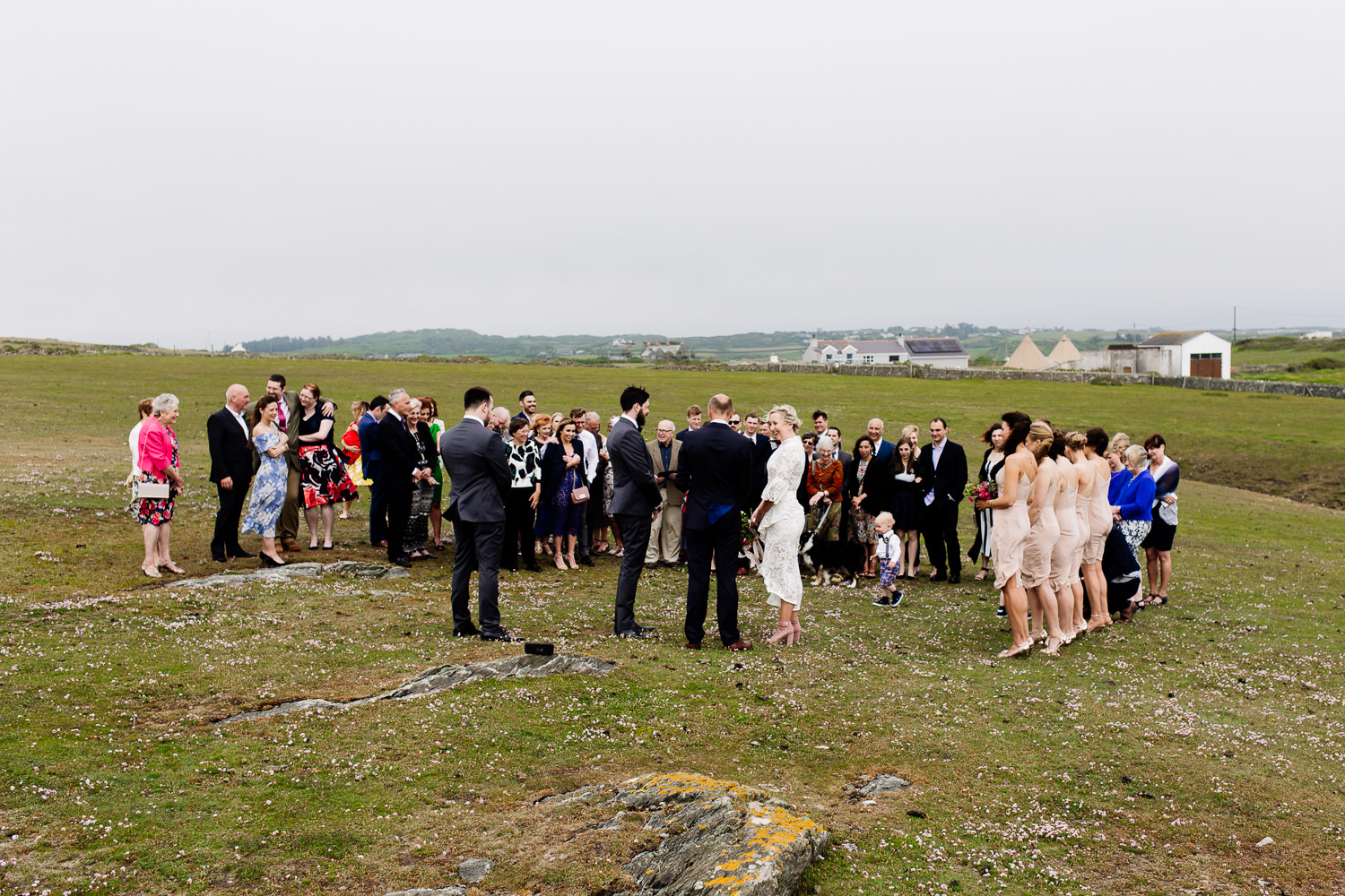 An outdoor ceremony on the headland in Anglesey at a festival theme tipi wedding by Wales wedding photographers Tom and Zoe.