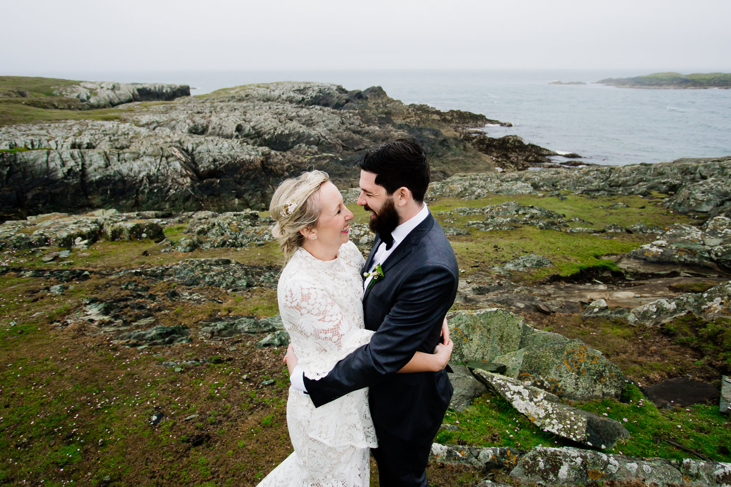 A bride and groom keeping warm on the cliffs in Anglesey, Wales.