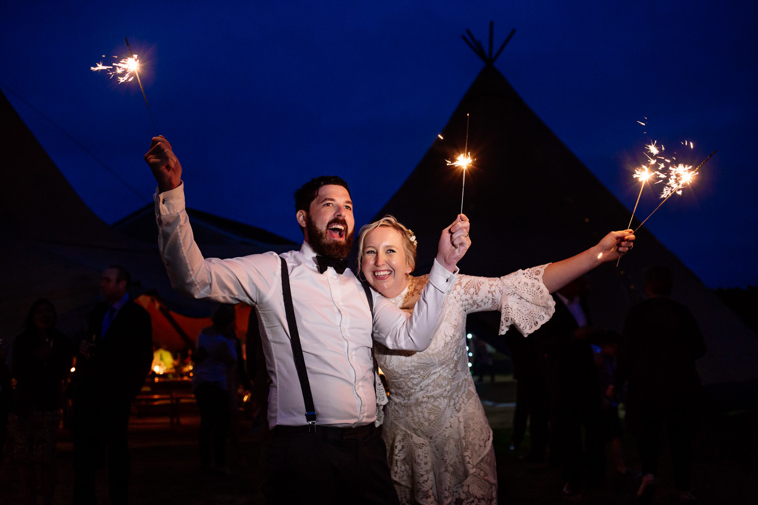 A bride and groom with sparklers in front of a tipi in Anglesey, Wales Wedding Photographer.